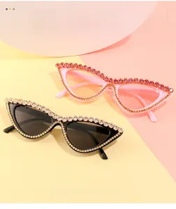 Détail de lunettes de soleil œil de chat serties de strass en rose et noir