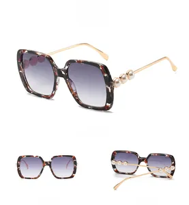 Detailed view of oversized tortoiseshell sunglasses with gold temples and white pearls