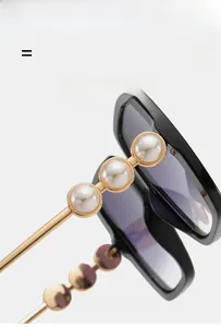 Detail shot of black sunglasses frame featuring luxury large pearls and gold accents
