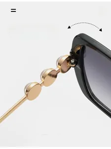 Detail of durable gold metal hinge with pearl accents on stylish black sunglasses