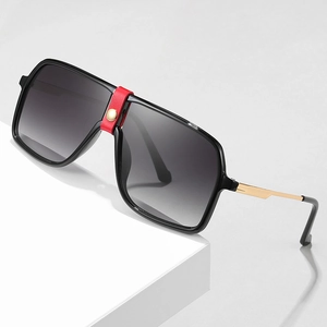 Black oversized square sunglasses featuring a red leather bridge with gold stud accents