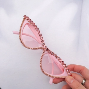 Lunettes de soleil œil de chat roses avec strass et verres teintés sur tissu blanc