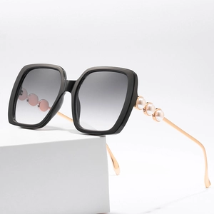 Fashionable oversized square sunglasses with pearl-decorated metal temples on white cube