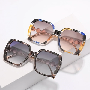 Square rhinestone sunglasses with marble and tortoiseshell patterns on white pedestals