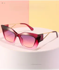 Close-up of cat-eye sunglasses with gradient wine red lenses and gold metal temples