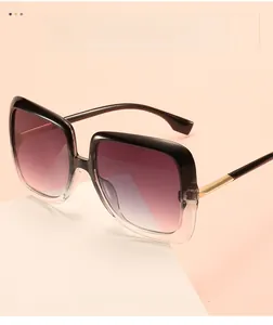 Detail view of square gradient sunglasses with gold metal temples on a geometric block