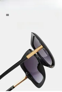 Detail of square oversized sunglasses showing golden metal hinges and black frame