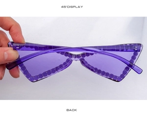 Détail de lunettes de soleil œil de chat violettes sans monture avec strass sur le bord