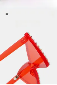 Gros plan de lunettes de soleil coeur sans monture rouges avec strass colorés et charnière
