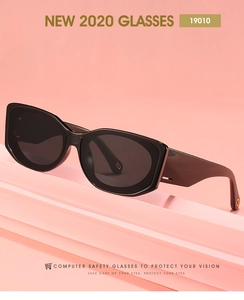 Gros plan de lunettes de soleil carrées noires avec détails métalliques sur fond corail
