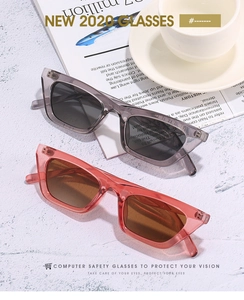 Close-up of trendy cat eye sunglasses in smoke grey and jelly orange frames on newspaper