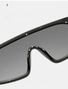 Detail einer übergroßen Sonnenbrille mit silbernen Kreuznieten und glatten Nasenpads