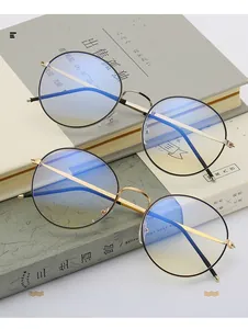 Detail of round metal glasses in gold and silver finish on a minimalist book background