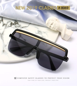 Close-up of shield sunglasses featuring gold chain-link metal trim on a black frame