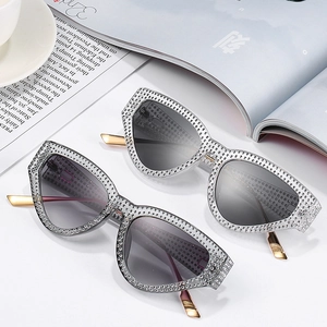 Cat eye sunglasses with rhinestone frames and gradient lenses on a marble surface