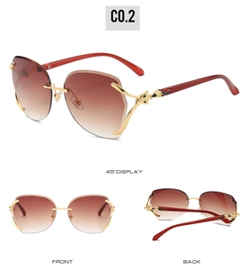 Detail view of gold metal fox head hinges and gradient brown lenses on rimless sunglasses