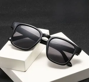 Detail of black square sunglasses with specs on polished temples and dark gray lenses