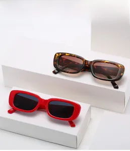 Close-up of retro rectangular sunglasses in leopard and red finishes on white podiums