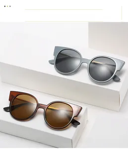 Gros plan de lunettes de soleil œil-de-chat bleu-gris et écaille sur socles blancs