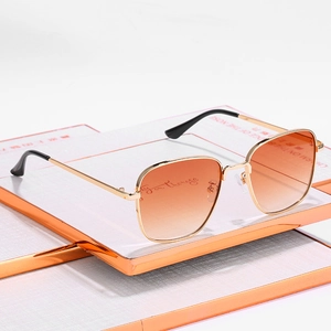 Retro small square metal sunglasses with orange gradient lenses on white textured surface