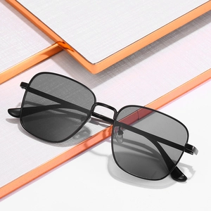 Retro square metal frame sunglasses with dark lenses on a minimalist white platform
