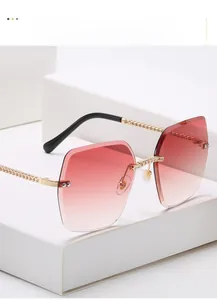 Detail of rimless square sunglasses with gradient red lenses and gold chain temples