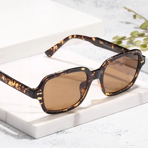 Square tortoise shell sunglasses with brown lenses on marble stone display block