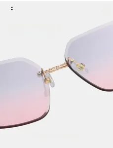 Macro detail of rimless sunglasses featuring a gold chain metal bridge and soft nose pads