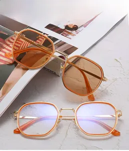 Détail de lunettes monture métallique polygonale avec verres orange et clairs sur magazines