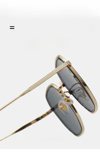 Détail de lunettes de soleil carrées avec monture dorée et branches élastiques