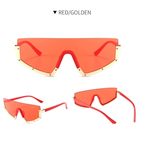Detail of red oversized shield sunglasses with golden metal trim and decorative studs