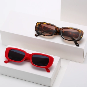 Fashionable rectangle sunglasses with red and tortoiseshell frames on white pedestals