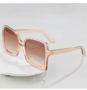 Detail view of large square champagne sunglasses with gradient lenses on ceramic plate