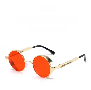 Detail of steampunk sunglasses with round red lenses and gold metal spring temples