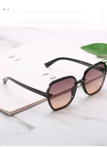 Detail view of large retro black sunglasses with purple to orange gradient lenses