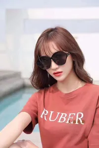 Detail of oversized retro oval sunglasses with dark lenses on model by the pool