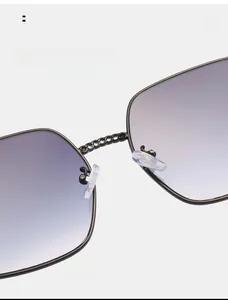 Close-up of square sunglasses with purple gradient lenses and black chain bridge detail