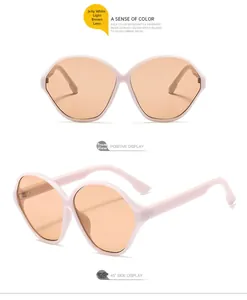 Detail view of oval oversized sunglasses with jelly white frame and light brown lenses