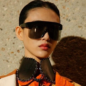 Lunettes de soleil oversize avec monture noire et verres gris foncé portées par mannequin