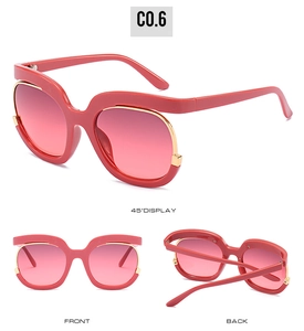 Detail view of oversized sunglasses with red frames, gradient lenses and gold cut-out trim