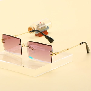 Frameless square sunglasses with pink gradient lenses and golden metal frame on a stand