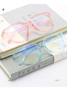 Detailed view of clear pink and blue round eyeglass frames stacked on books