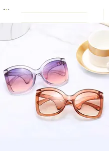 Detail of oversized sunglasses with metal hinges on a marble table with coffee cup