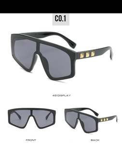Detail view of oversized sunglasses with golden rivets and dark grey lenses in black frame