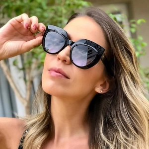 Close-up of trendy oversized cat-eye sunglasses with polished black frames on a model