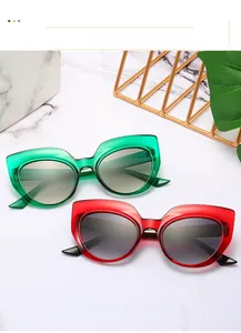 Close-up of trendy oversized cat eye sunglasses in translucent green and bold red frames