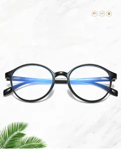 Close-up of black round anti-blue light glasses on white marble surface with green leaf
