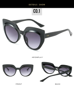 Detail view of black oversized cat eye sunglasses with gold accents and gradient lenses