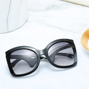Fashionable oversized sunglasses with black glossy frames and grey gradient lenses