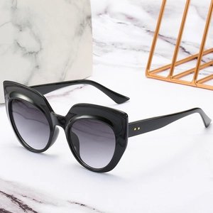 Fashion cat-eye sunglasses with black frame and gradient lenses on marble background